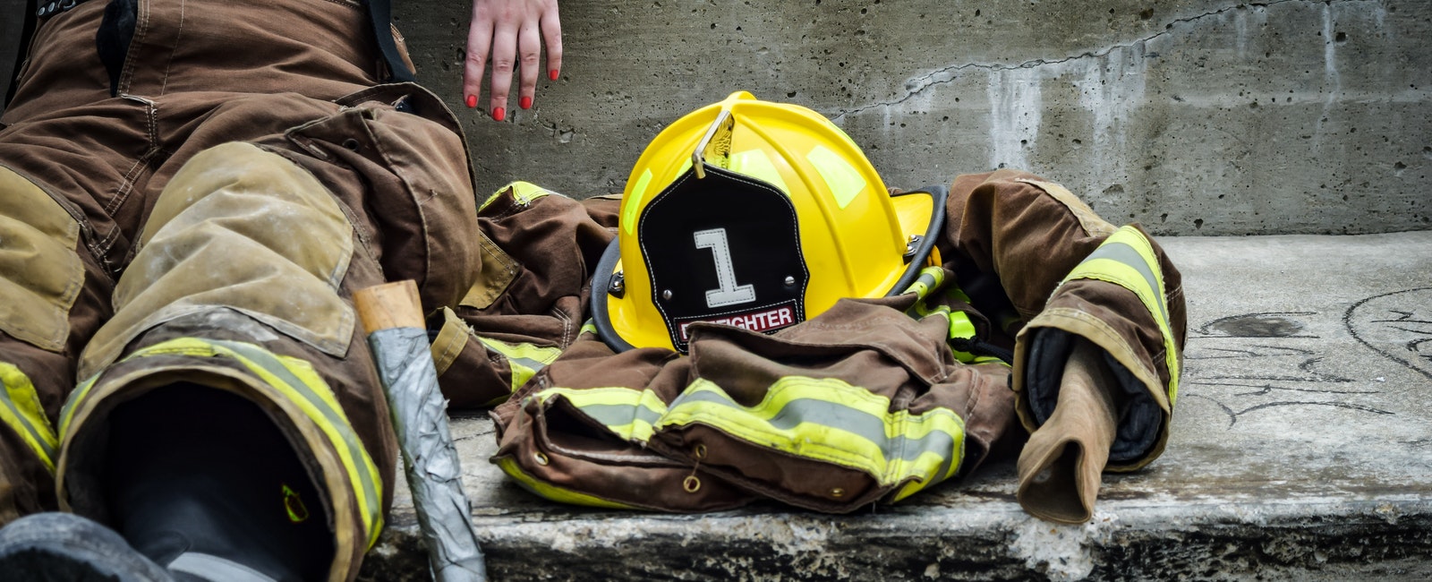 Yellow firefighter helmet and brown firefighter suit laying on the ground